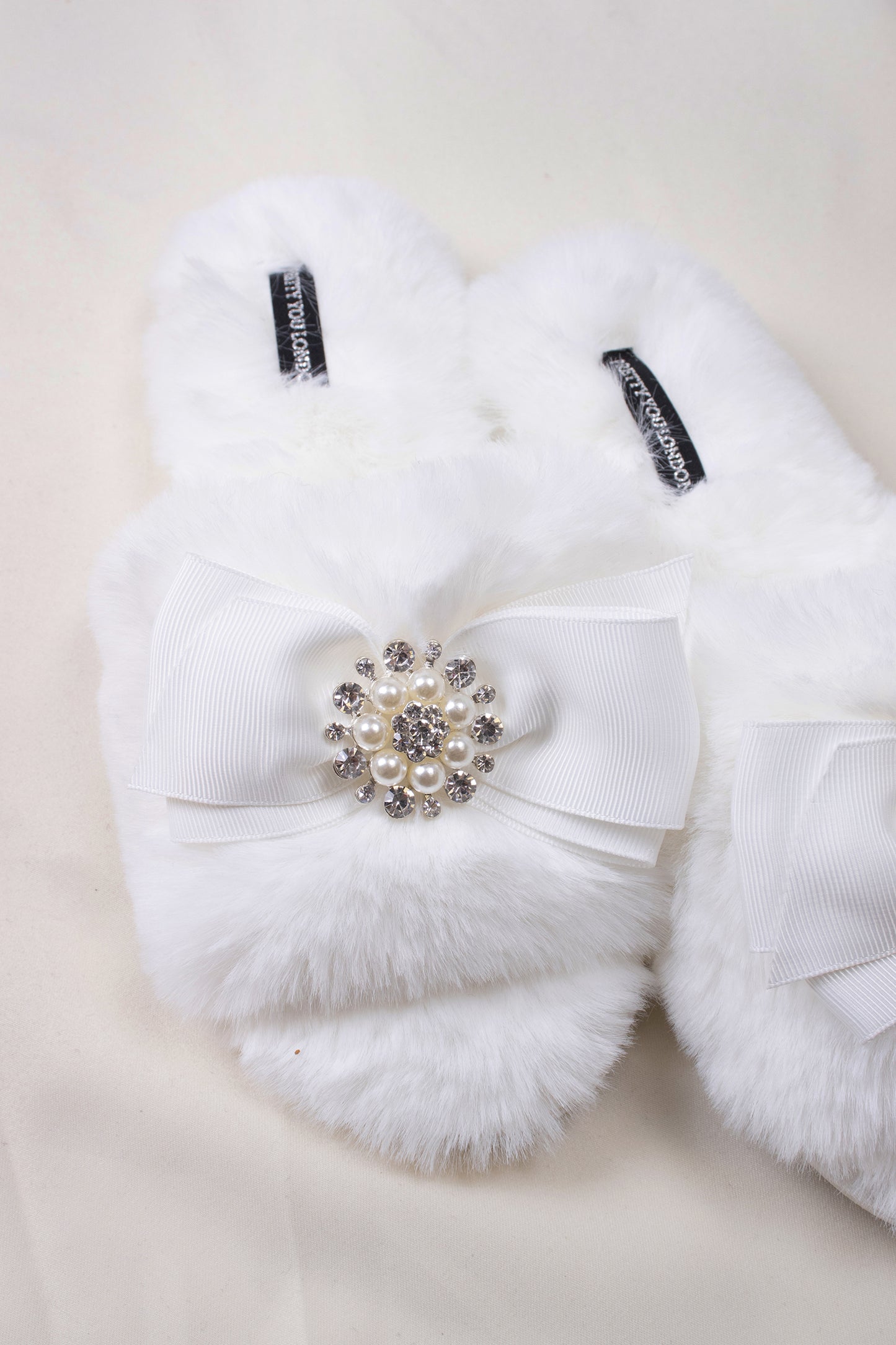 
                  
                    Anya women's slider slippers in cream using the softest faux furs and topped with a premium grosgrain bow finished with a jewel pearl embellishment from Pretty You London
                  
                