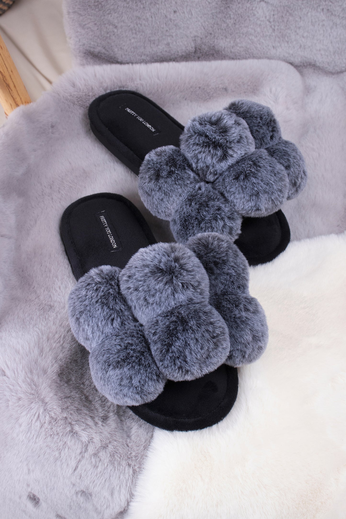 
                  
                    Dolly women's slider slippers in black with oversized faux fur pom poms from Pretty You London
                  
                